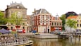 A canal with a boat docked on the left, surrounded by historic buildings with red and white facades.