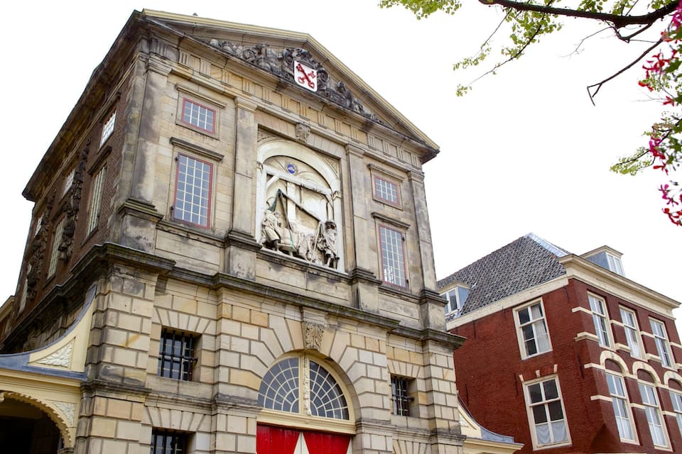En historisk bygning med et tårn med et ur, detaljerede stenskurringer og en rød markise.