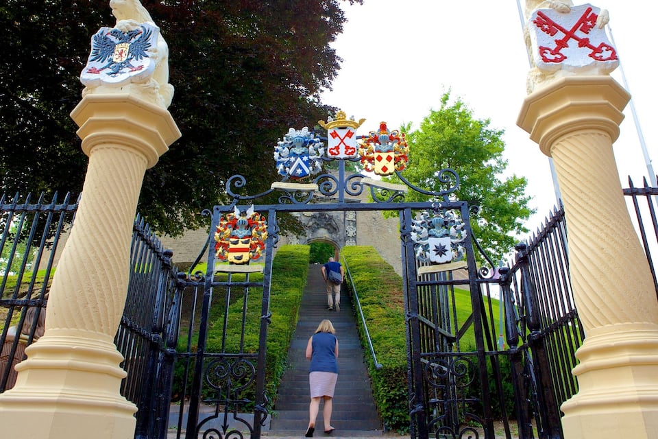 Une porte ornée d’écussons et un escalier menant à un bâtiment.