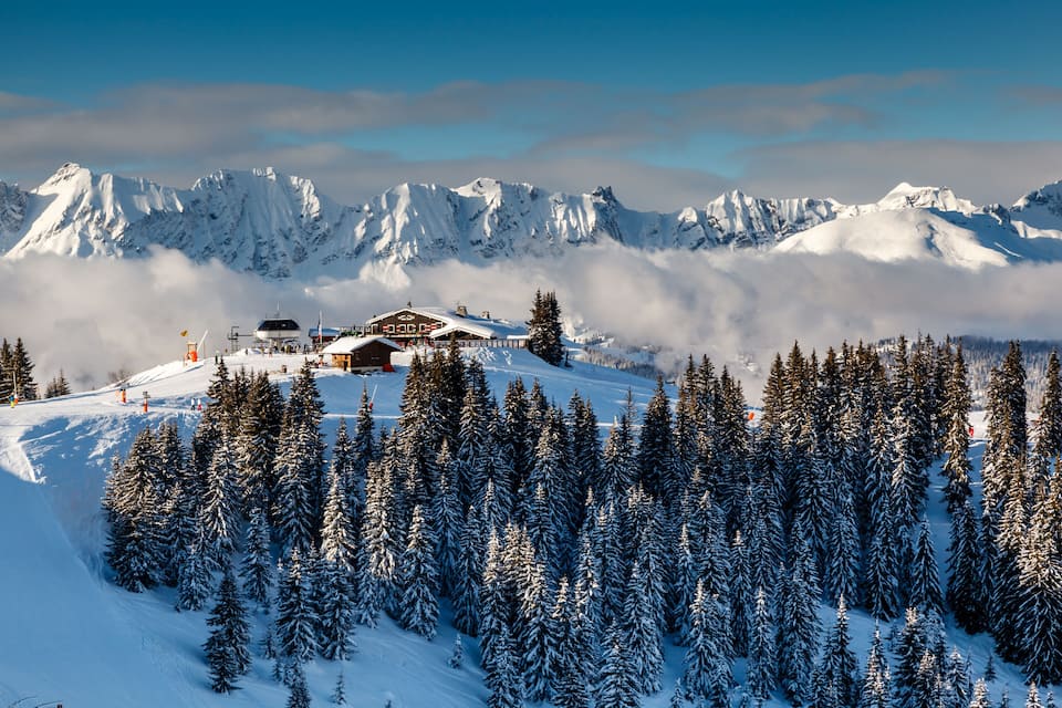 Een met sneeuw bedekte bergketen met een lodge en skipistes.