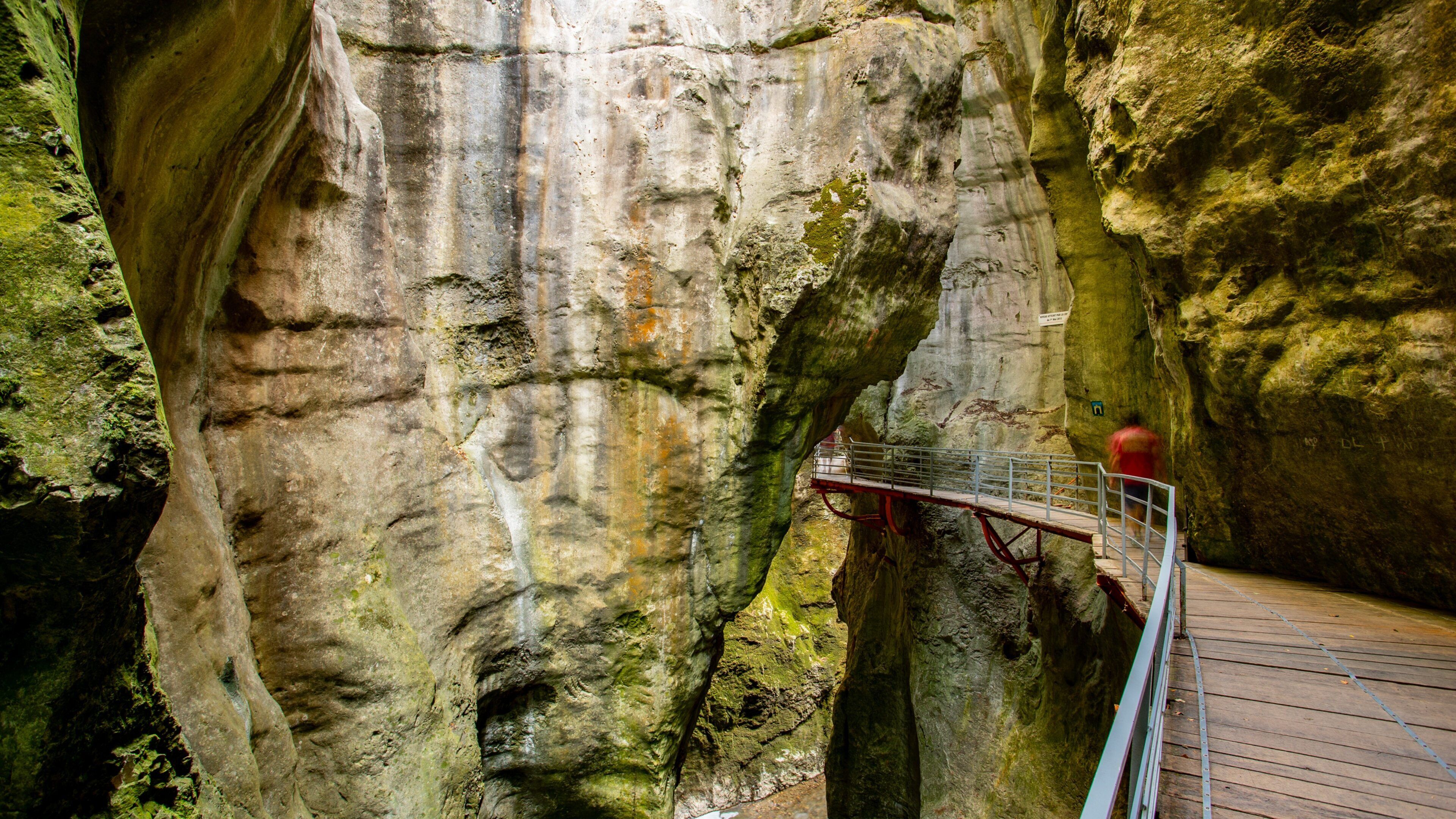 A rocky cave with a wooden walkway and metal railing.