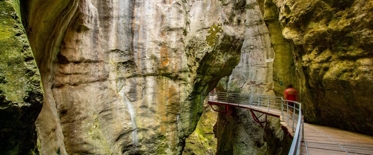 A rocky cave with a wooden walkway and metal railing.