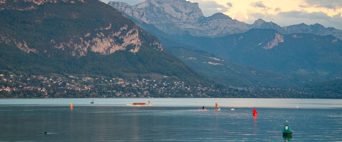A lake with mountains in the background and a town on the shore.
