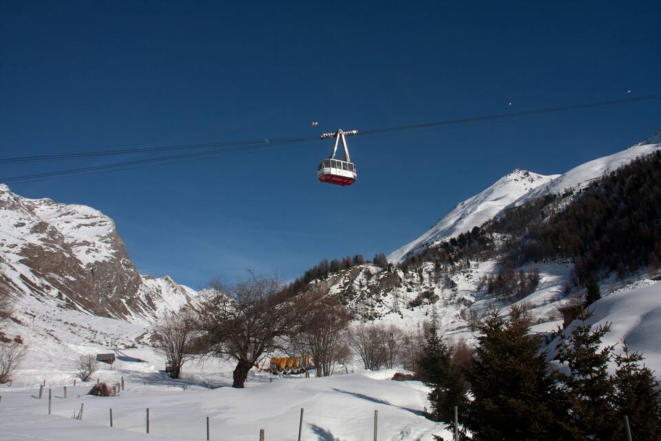 A cable car moving over a snowy mountain landscape.
