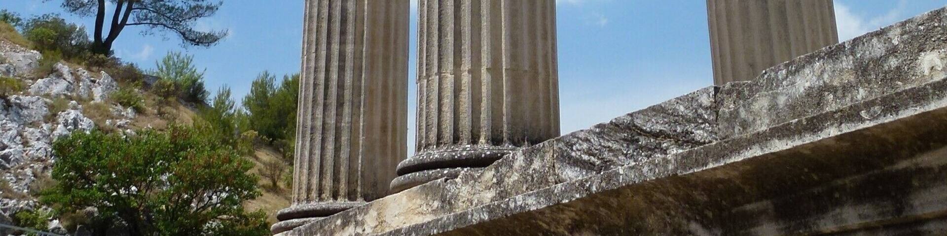 Una estructura clásica con columnas y frontón triangular, sobre un cielo despejado con nubes dispersas.