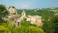 Une église historique en pierre, dotée d’un clocher, entourée d’une végétation luxuriante et d’un paysage rocheux.