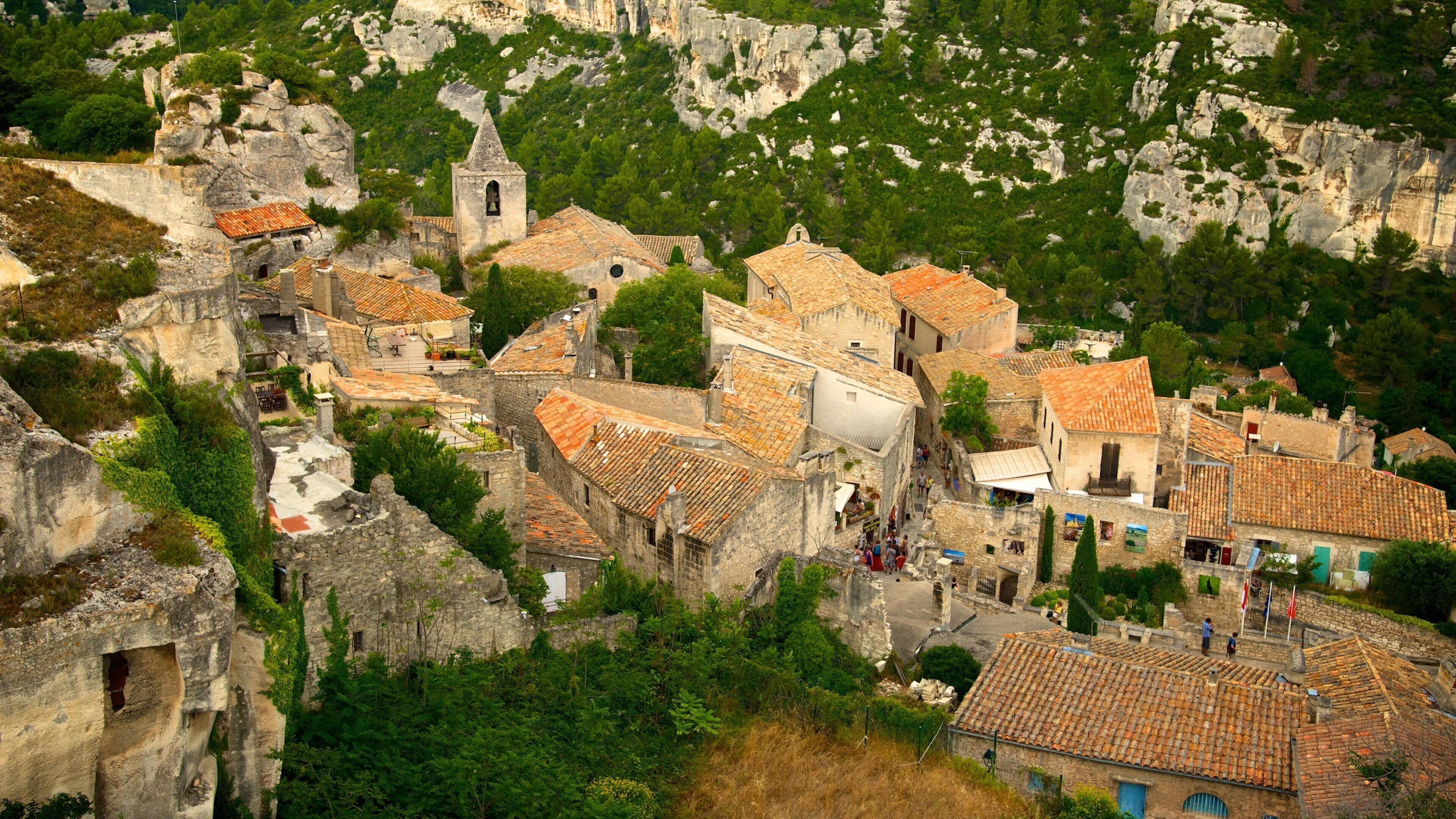 Un village aux bâtiments en pierre et aux toits de tuiles, niché dans une région montagneuse et verdoyante.