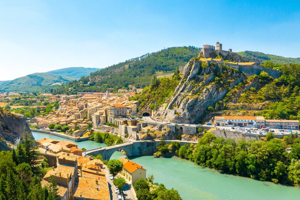 A historic town with a river, a bridge, and a castle on a hill.