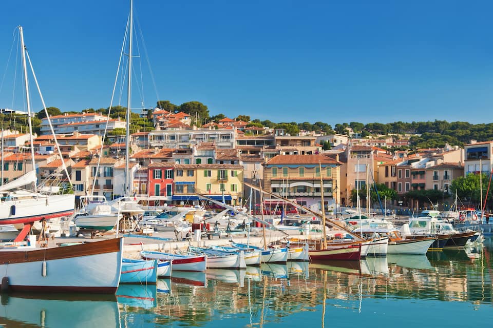 A marina with numerous boats docked, surrounded by colorful buildings and a clear blue sky.