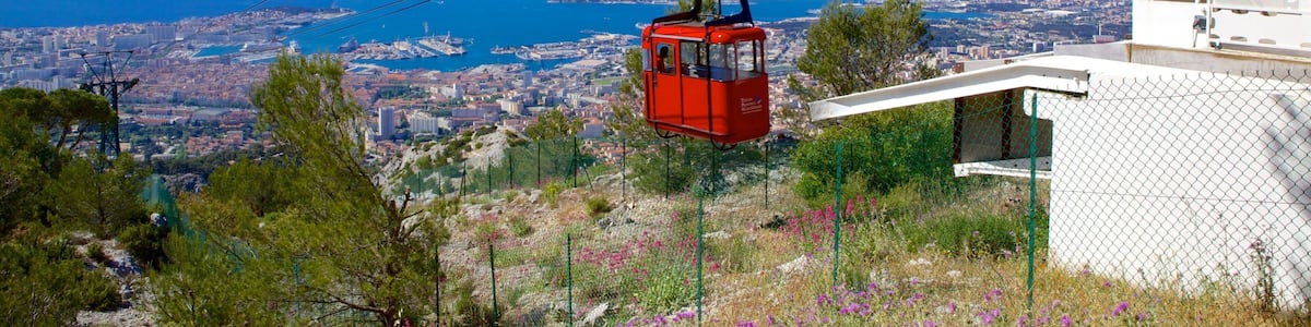 A red cable car over a coastal city with a clear blue sky.
