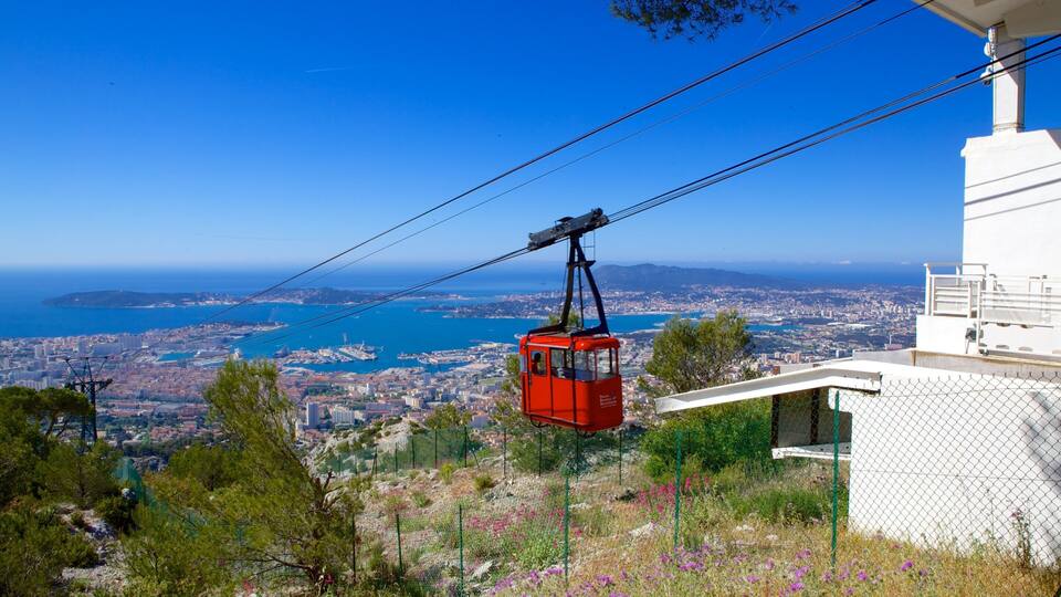 A red cable car over a coastal city with a clear blue sky.