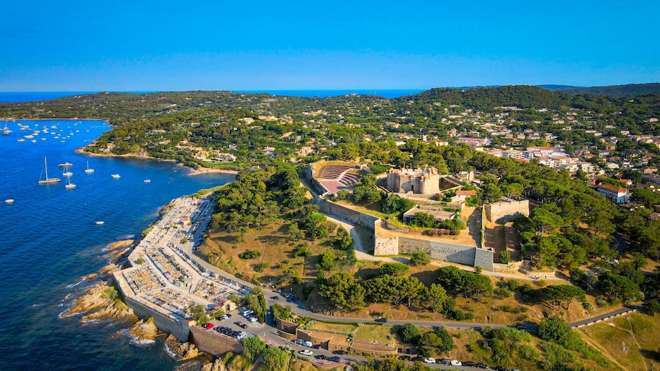 A coastal town with a historic fort, a marina with boats, and a densely built residential area.