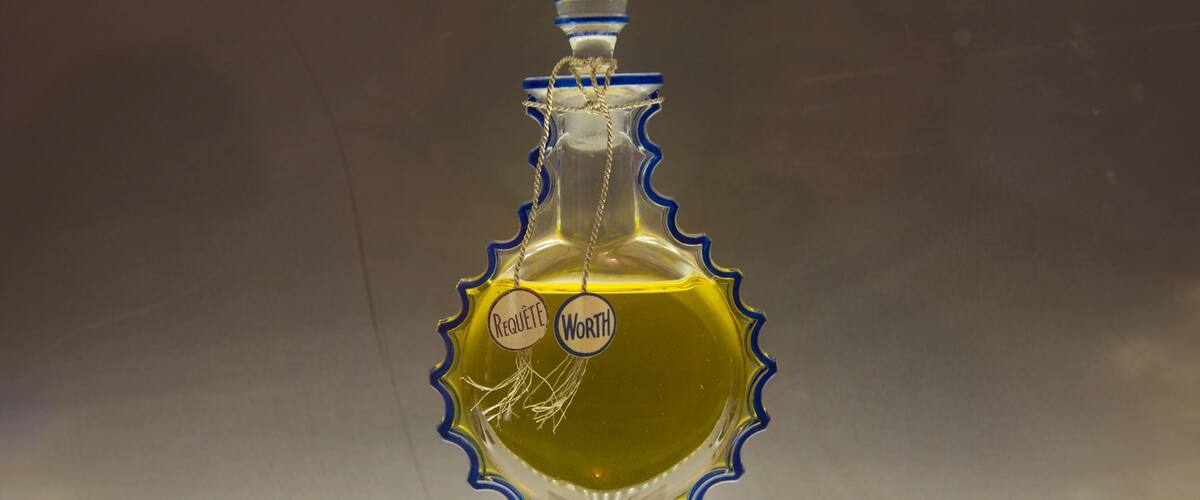 A decorative bottle with a blue and gold design, labeled "Requête" and "Worth."