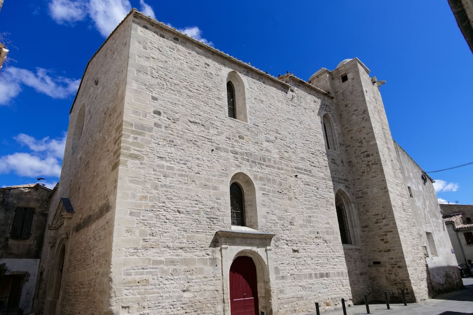 Um edifício histórico de pedra com porta vermelha e janelas em arco.