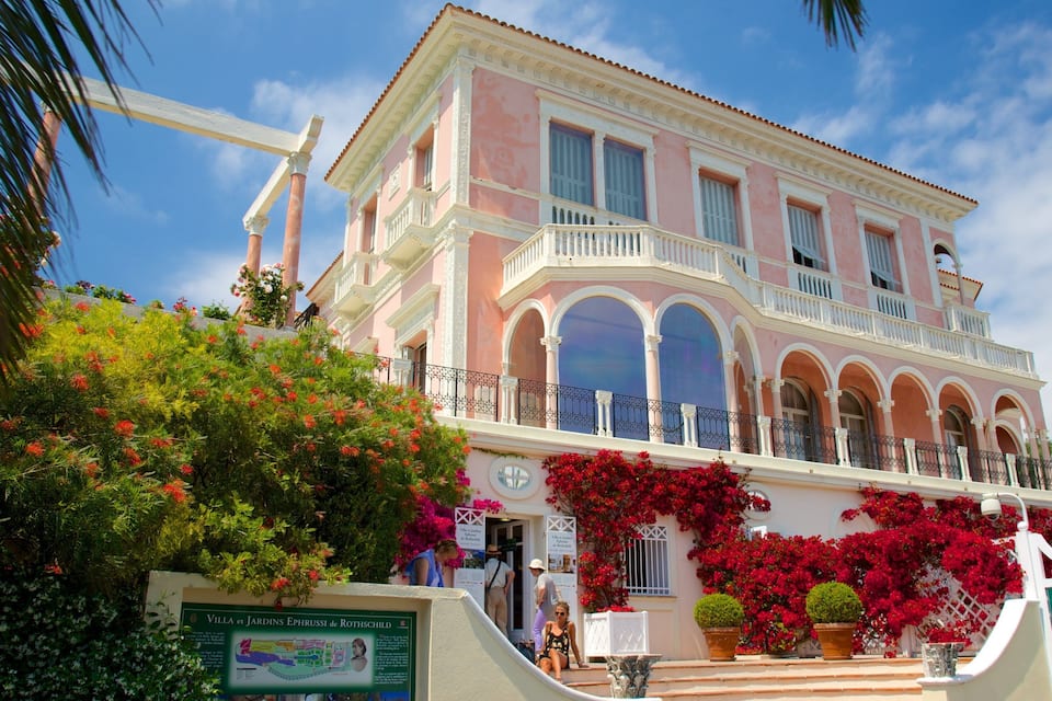 Villa et Jardins Ephrussi de Rothschild with pink and white architecture, arched windows, and lush greenery.