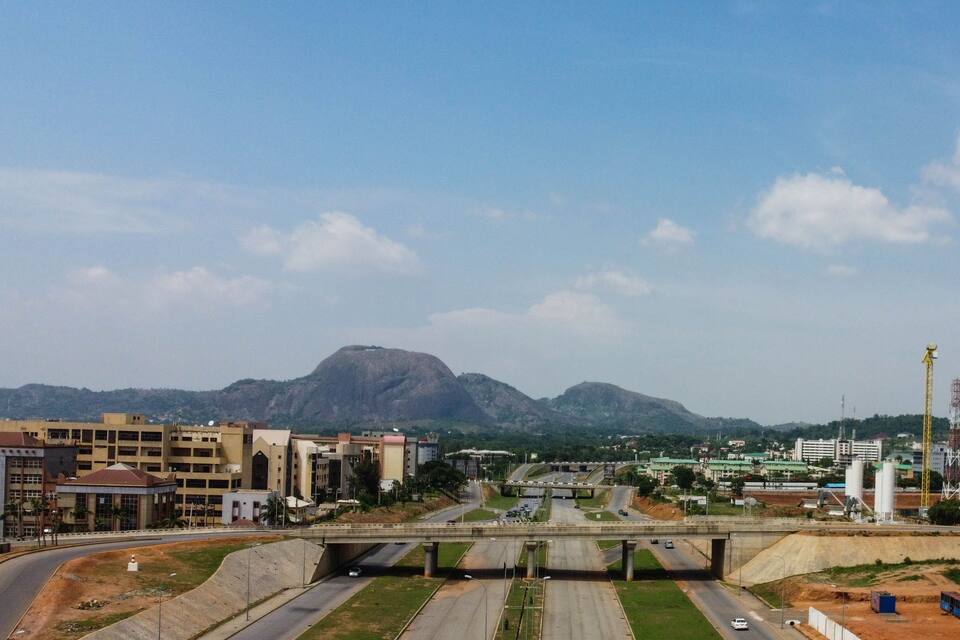 A highway with a bridge, buildings, and mountains in the background.