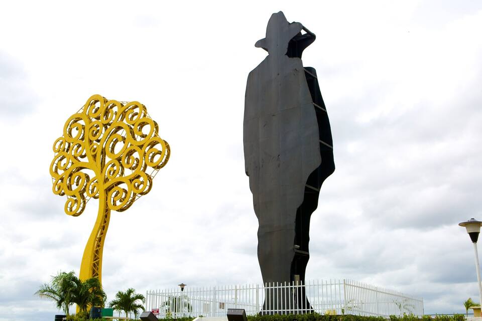 Una gran escultura de una persona y un árbol con complejos diseños dorados.