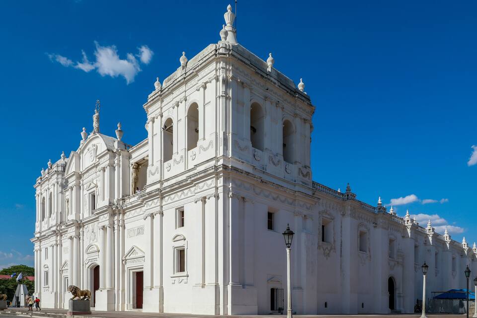 A white colonial-style church with a bell tower and statues, set against a clear blue sky.