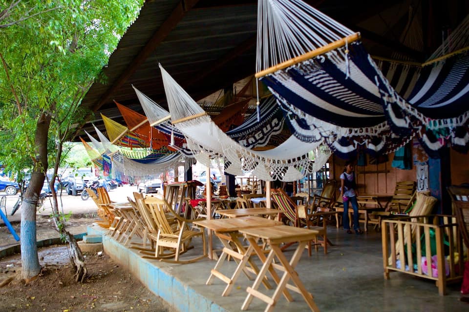 Un área de estar al aire libre con techo, con hamacas y muebles de madera.