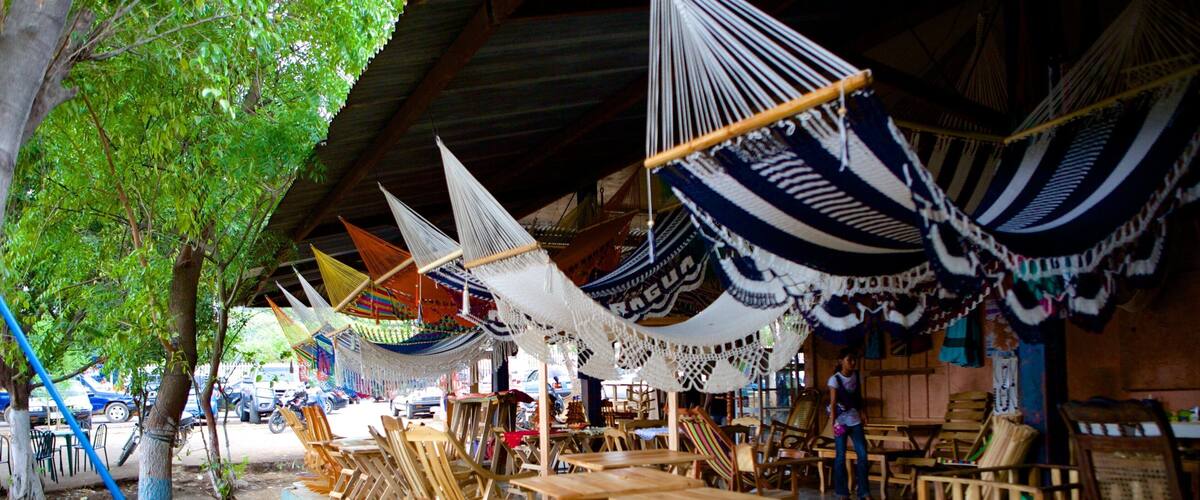 A covered outdoor seating area with hammocks and wooden furniture.