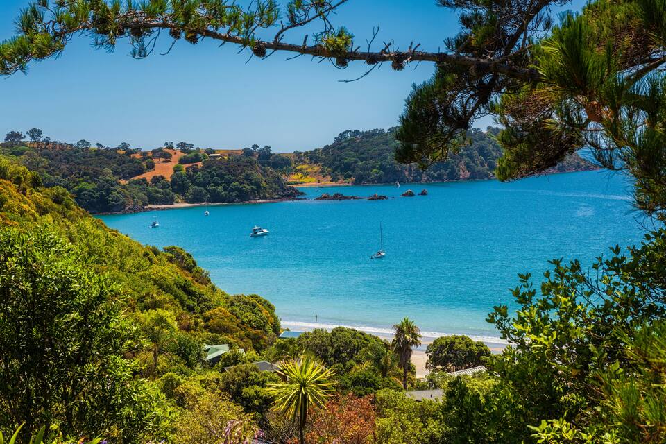 A coastal landscape with a clear blue sea, boats, and lush greenery.