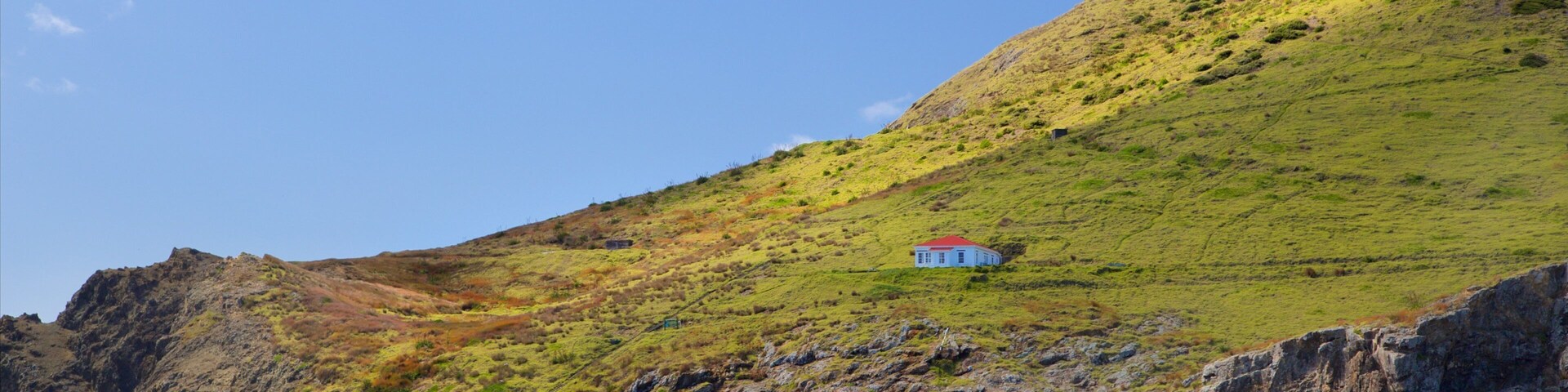 Cape Brett Lighthouse ofreciendo una bahía o un puerto, un faro y costa rocosa