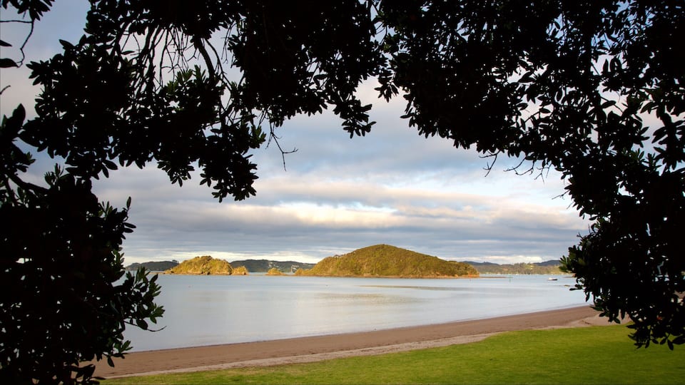 A lake with a grassy shore and a hill in the distance.