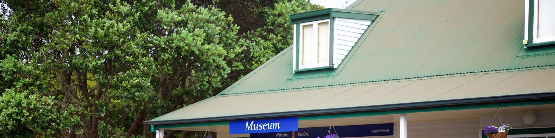 A museum with a green roof, a blue entrance, and hanging flower baskets.