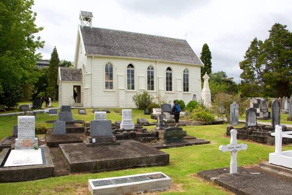 Un cimetière avec des pierres tombales blanches, une église et une croix sur le toit.