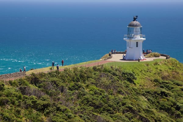 A lighthouse on a grassy hill overlooking the ocean.