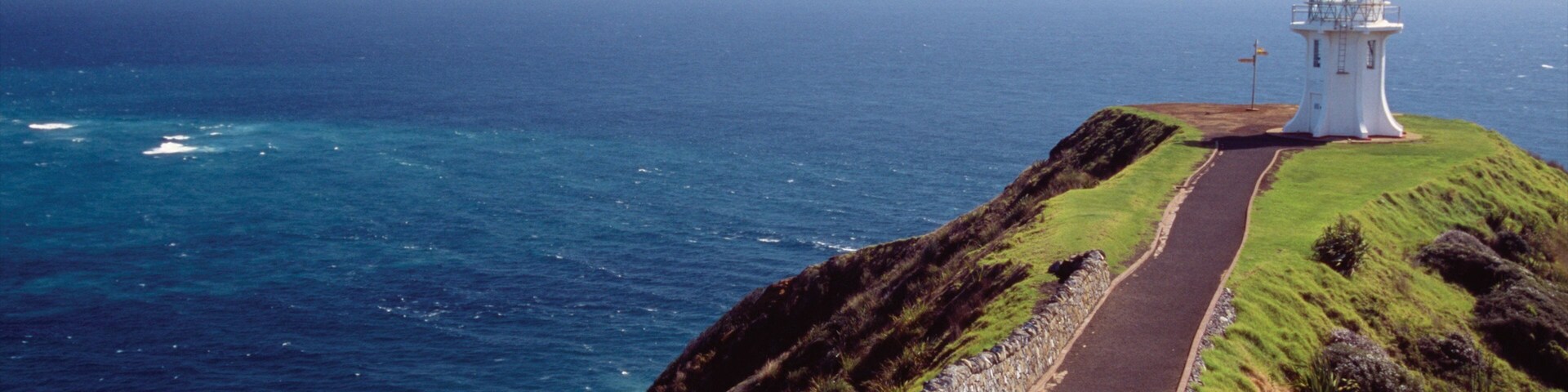 Cape Reinga Lighthouse featuring rocky coastline and a lighthouse