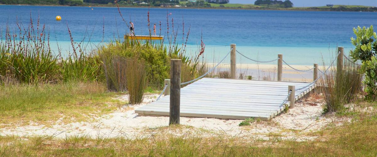 Una playa con un paseo marítimo de madera que conduce a una torre de salvavidas.