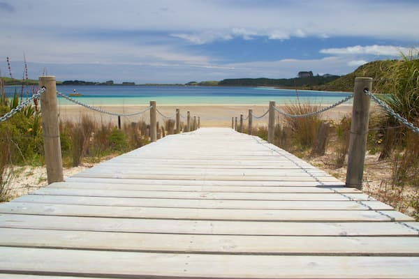 A wooden boardwalk leading to a beach with clear turquoise water.