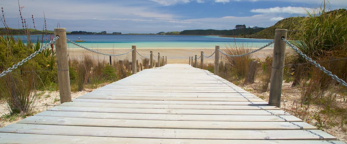 A wooden boardwalk leading to a beach with clear turquoise water.