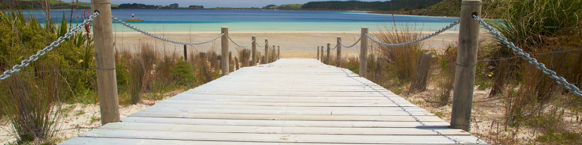 A wooden boardwalk leading to a beach with clear turquoise water.