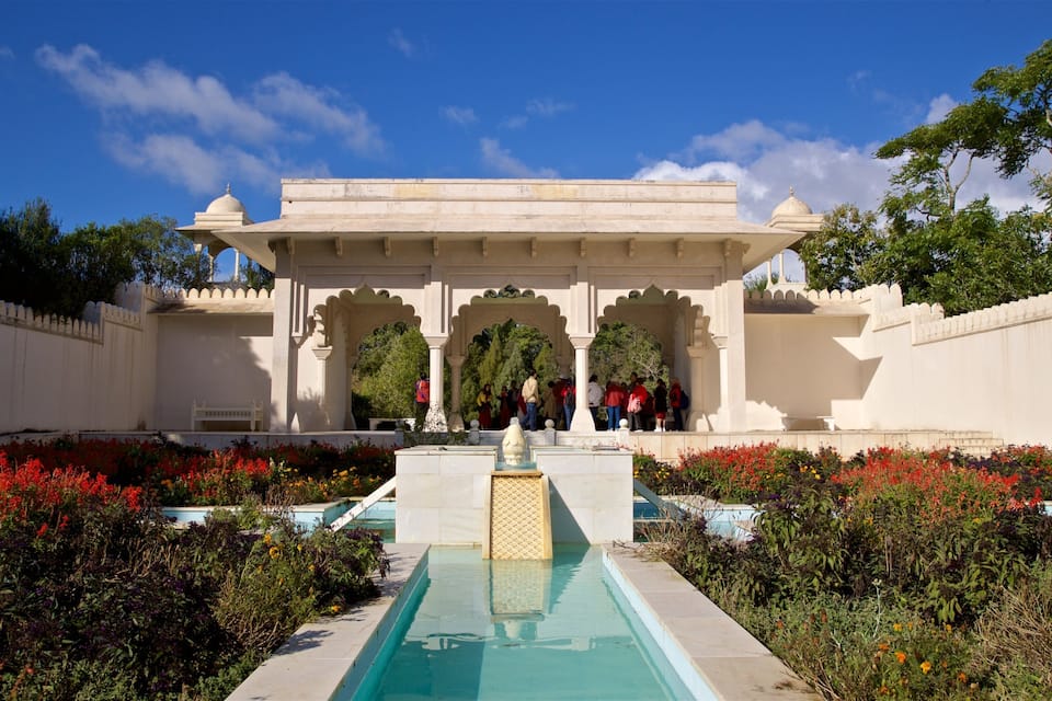 Un jardí indi tradicional amb una piscina, un pabelló i un grup de persones.