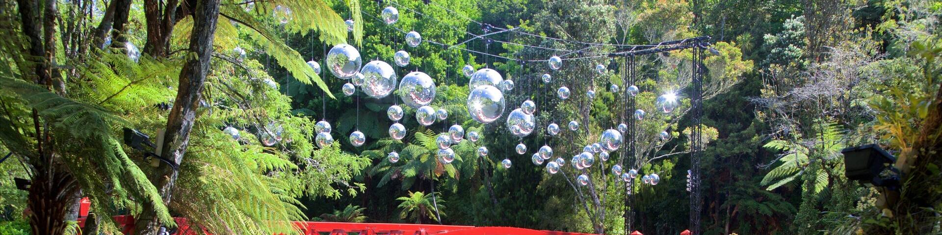 A red bridge over a river with reflective spheres hanging above.