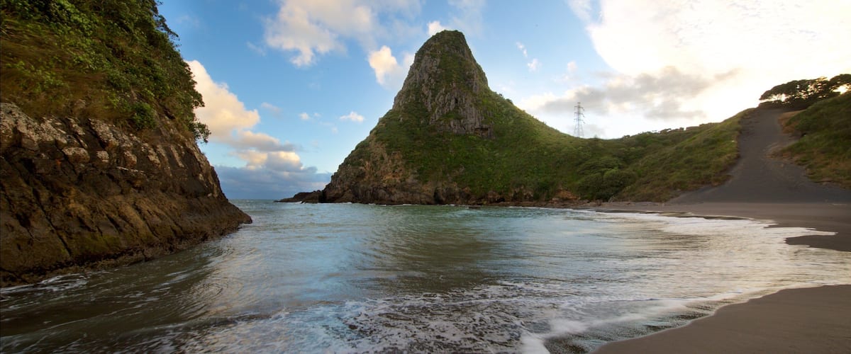 Paritutu Rock featuring a sunset, a bay or harbour and a sandy beach