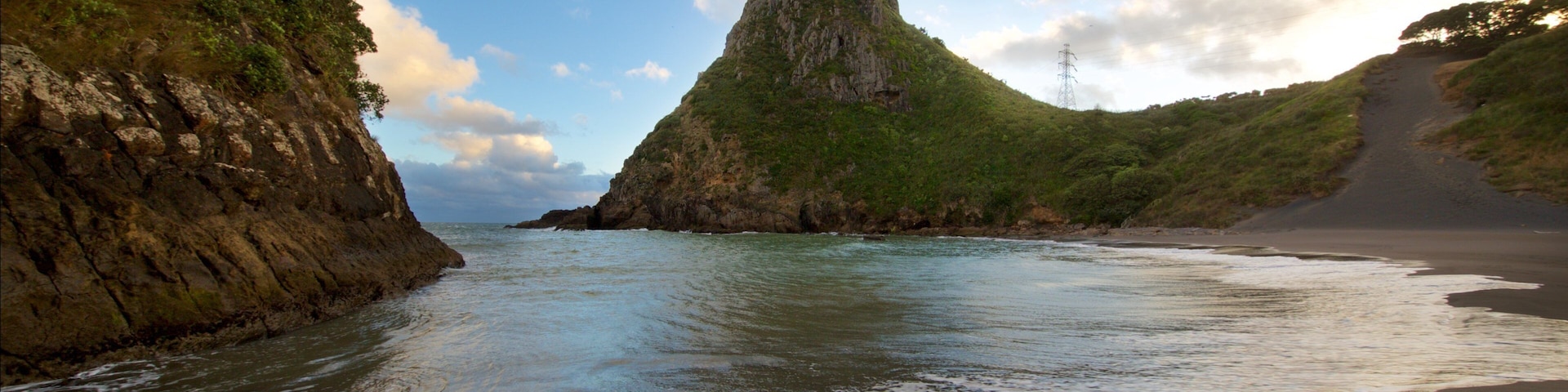 Paritutu Rock featuring a beach, a bay or harbor and a sunset