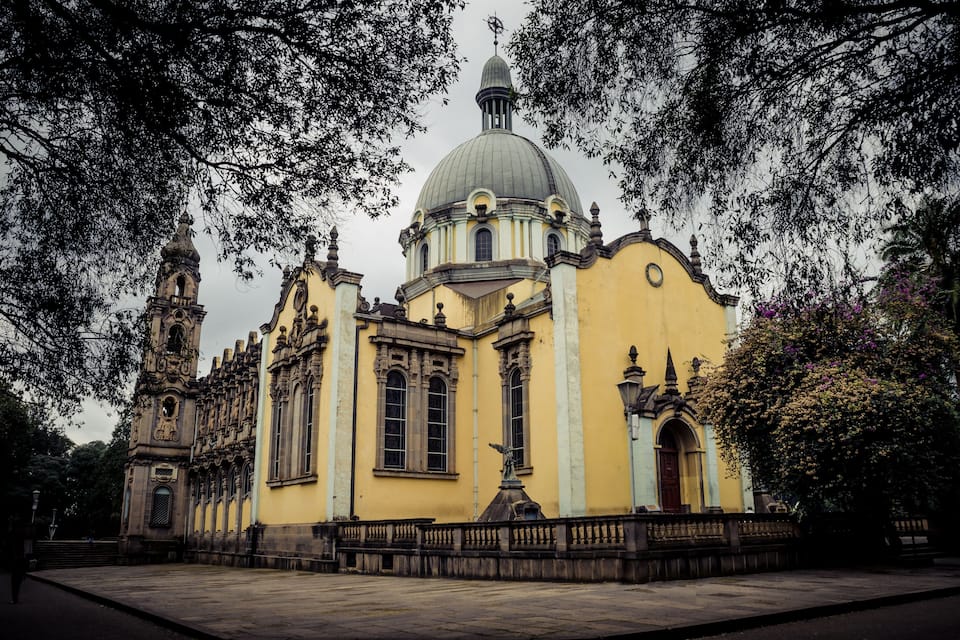 Um edifício amarelo histórico com uma cúpula e um campanário.