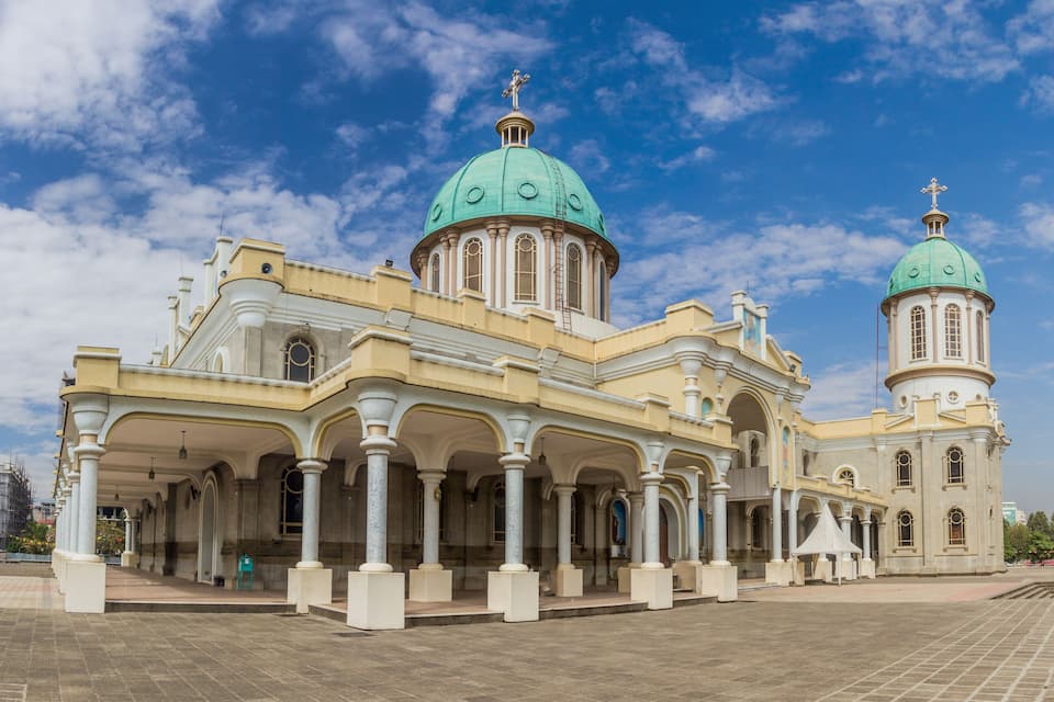 Uma igreja grande com duas cúpulas verdes e um campanário.