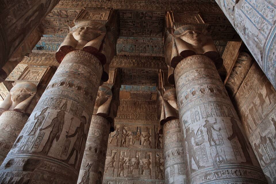 Antike ägyptische Säulen mit Hieroglyphen und einer Decke mit aufwendiger Kunst.