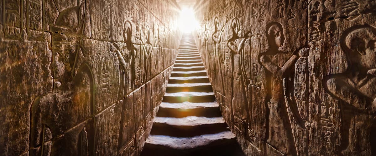 A stone staircase with hieroglyphs leading to a bright light at the top.