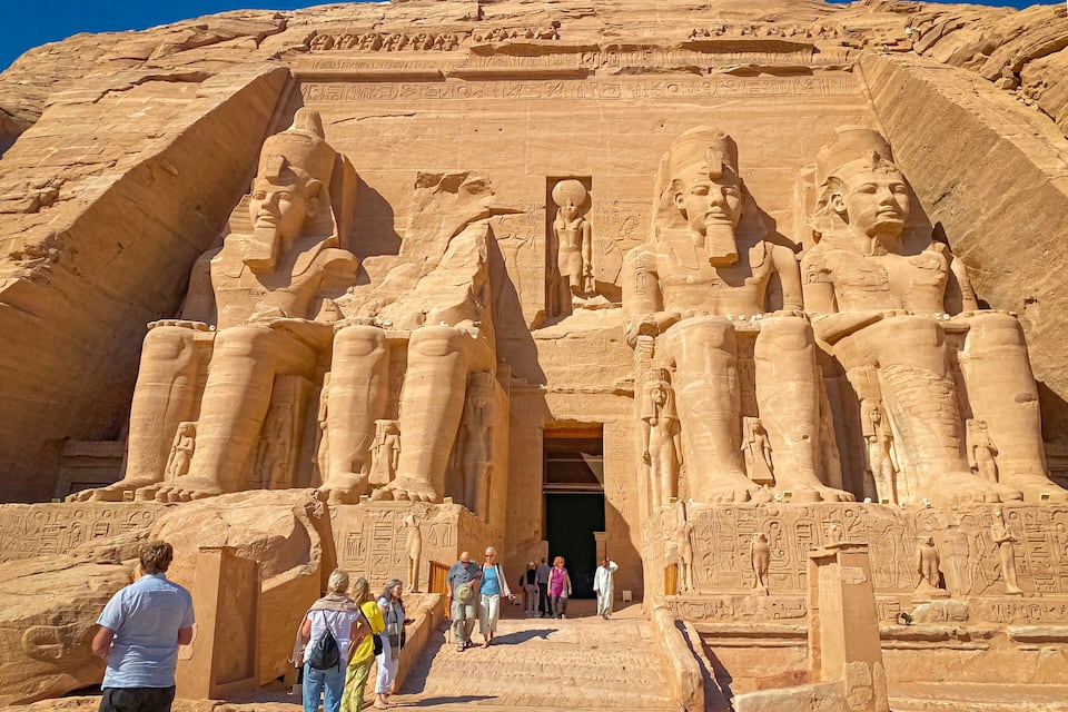 Un vaste temple de l’Égypte ancienne, orné de statues colossales de pharaons et de hiéroglyphes.