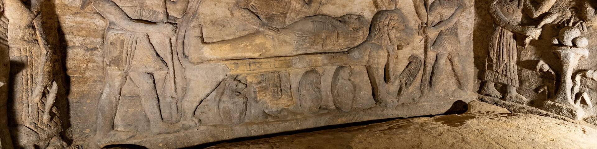 A carved stone relief depicting ancient Egyptian figures and hieroglyphs.