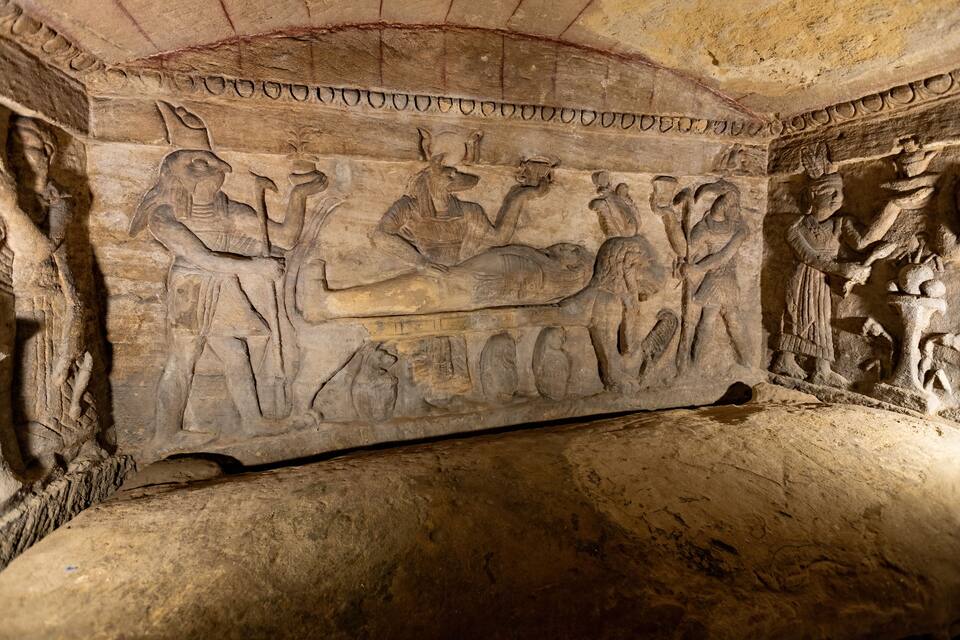 A carved stone relief depicting ancient Egyptian figures and hieroglyphs.