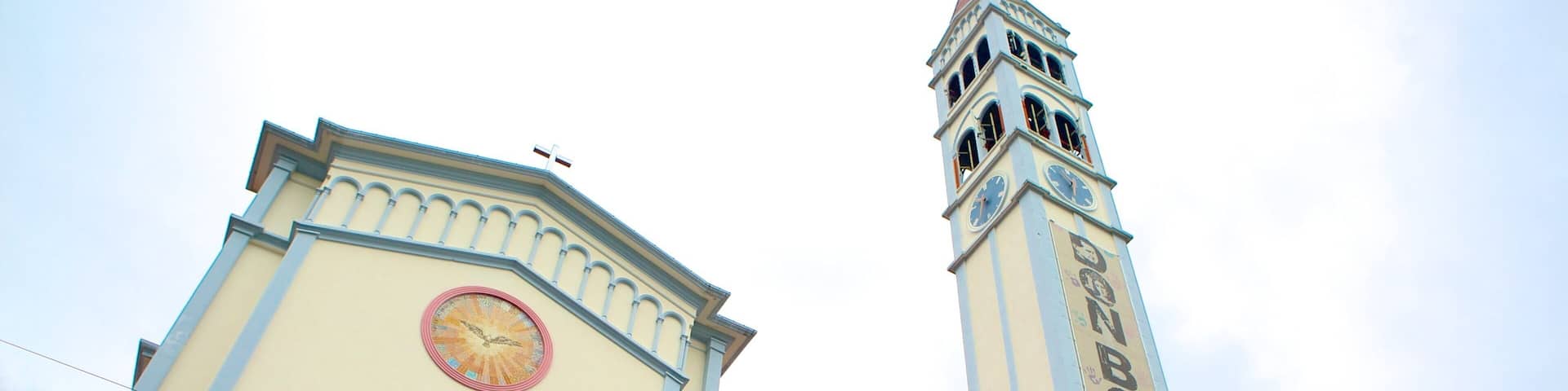 A church with a clock tower and a mural of a saint.
