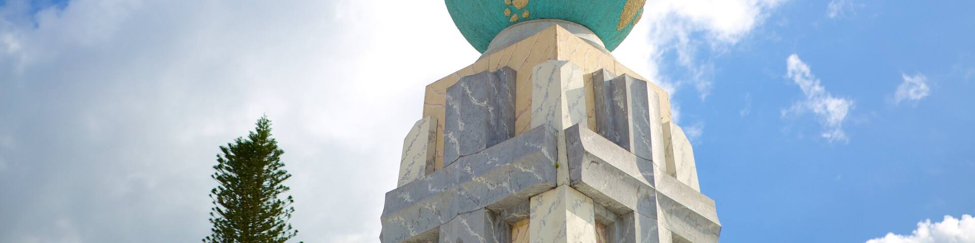 A statue on top of a globe with a clear sky in the background.