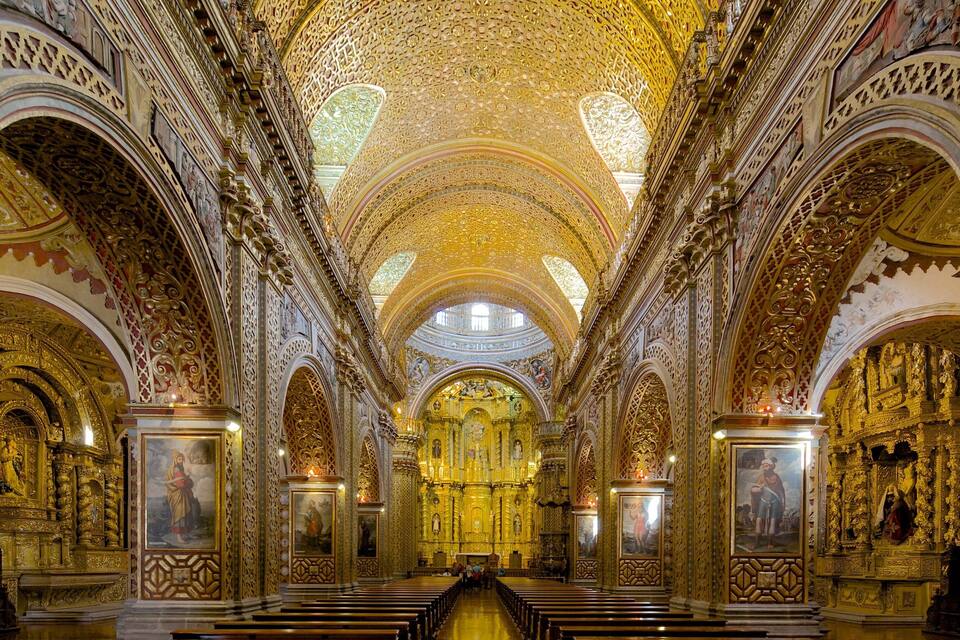An ornate church interior with intricate golden decorations and a central altar.