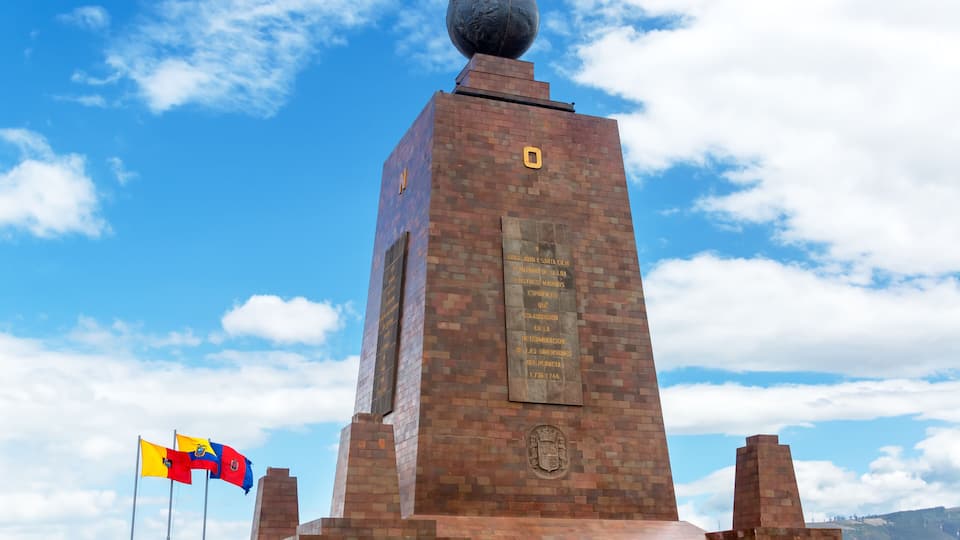 A brick monument with a globe on top, flags, and a plaque.